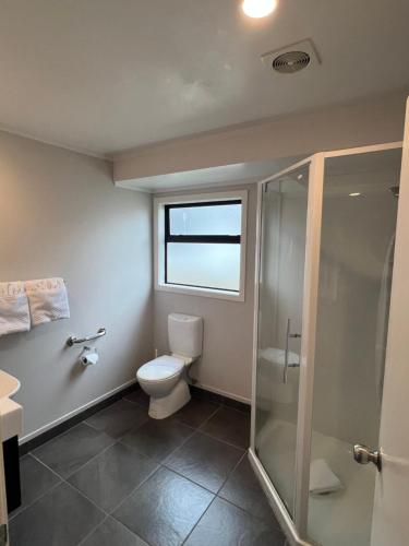 a bathroom with a toilet and a glass shower at Quality Inn Acapulco Taupo in Taupo