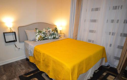a bedroom with a yellow bed with two lamps at Dorvic Cottage in Bridgetown