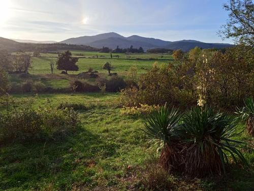 a field of grass with mountains in the background at Maison calme avec piscine entourée de son parc in Quintenas