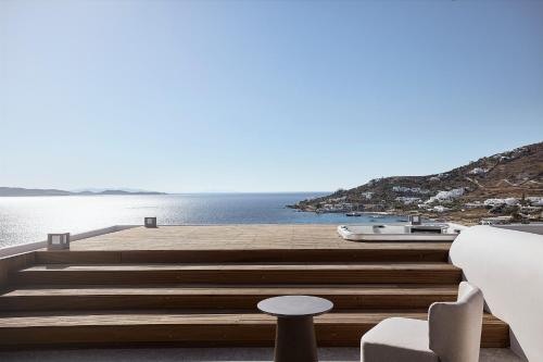 a wooden dock with a boat on the water at Amazon Mykonos Suites & Spa in Agios Ioannis Mykonos