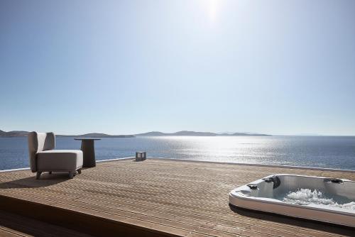 a bath tub sitting on a wooden deck next to the water at Amazon Mykonos Suites & Spa in Agios Ioannis Mykonos