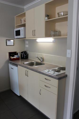 a kitchen with white cabinets and a sink at Quality Inn Acapulco Taupo in Taupo