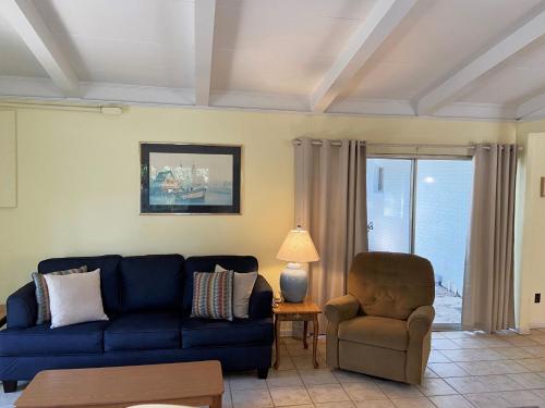 a living room with a blue couch and a chair at SEA COTTAGE APARTMENT Duplex in Jekyll Island