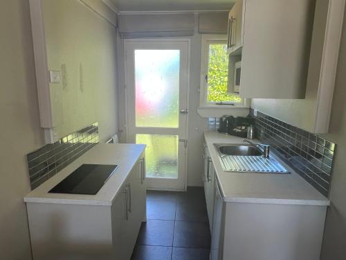a white kitchen with a sink and a window at Quality Inn Acapulco Taupo in Taupo