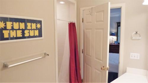 a bathroom with a red shower curtain next to a door at GUIDING LIGHT UNIT C - GROUNDFLOOR apts in Jekyll Island