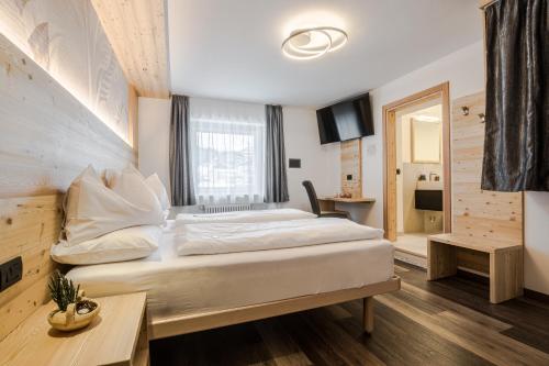 a bedroom with a large white bed in a room at HOTEL B&B MARILENA in Arabba