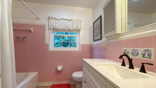a pink bathroom with a sink and a toilet at HERON COTTAGE home in Jekyll Island