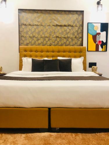 um quarto com uma cama grande e uma cabeceira amarela em PANACHE by VG em Lonavala
