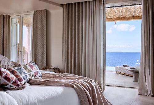 a bedroom with a bed and a view of the ocean at Amazon Suites in Agios Ioannis Mykonos