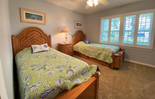 a bedroom with two beds and two windows at THE SALTY SOL home in Jekyll Island
