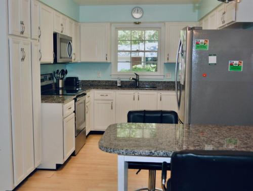een keuken met witte kasten en een roestvrijstalen koelkast bij A JEKYLL INTERLUDE home in Jekyll Island