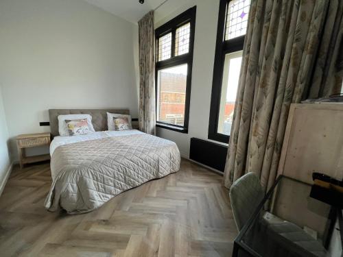 a bedroom with a bed and two windows at Boutique Hotel de Kade Zaandam-Amsterdam in Zaandam