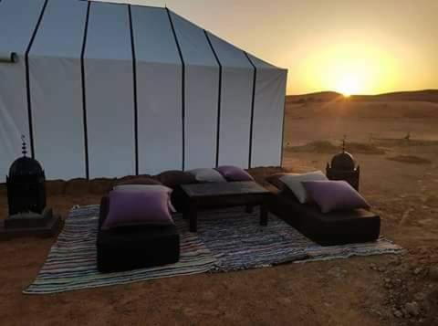 a living room with a couch and chairs in the desert at Khadija Desert Camp in Merzouga