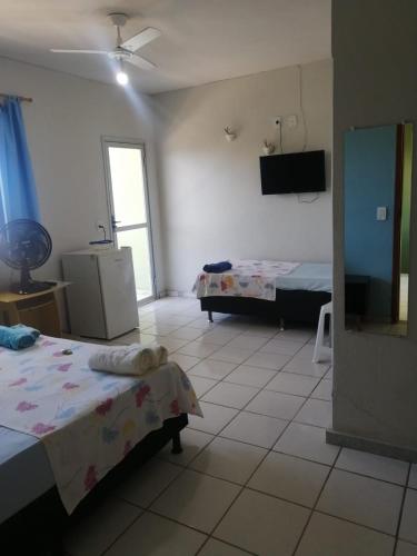 a room with two beds and a television in it at Aquarela Suítes in Piúma