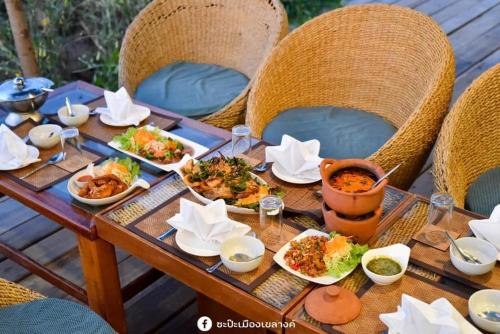 a wooden table with plates of food on it at KEPT Cabana เคปท์ คาบานา in Lampang