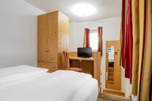 a bedroom with a bed and a desk with a television at HOTEL B&B MARILENA in Arabba