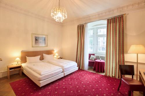 a bedroom with a large white bed and a red rug at Hotel Markgräfler Hof in Karlsruhe