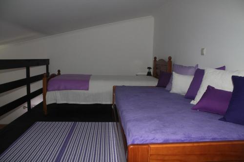 a bedroom with two beds with purple and white pillows at Refugio no Campo in Rapoula do Côa