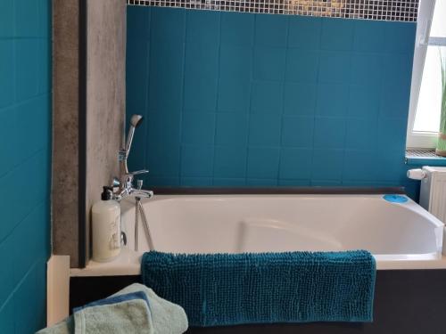 a bathroom with a white tub with a blue wall at Studio AU CENTRE de Chimay, arrivee autonome in Chimay
