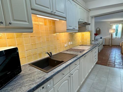 a kitchen with white cabinets and a sink at Villa MahJong Piscine Vue Mer Clim 6 adultes et 2 enfants in Cavalaire-sur-Mer