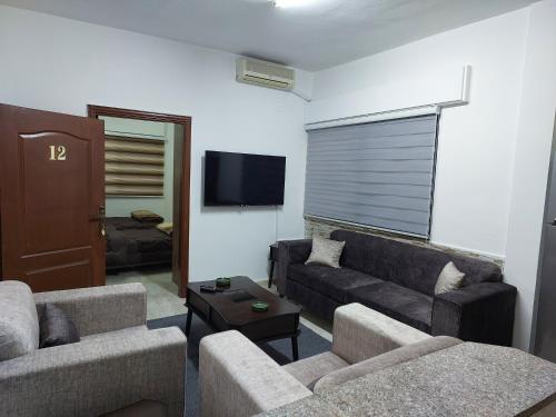 a living room with two couches and a flat screen tv at Cozy Home 2 in Amman