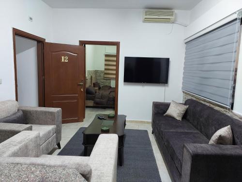 a living room with two couches and a tv at Cozy Home 2 in Amman