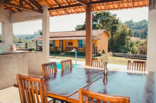 a dining room table with chairs and a view of a house at Fazenda do Engenho in Ritápolis