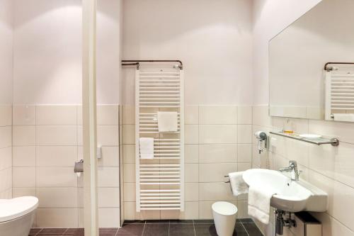 a white bathroom with a sink and a shower at Hotel Markgräfler Hof in Karlsruhe