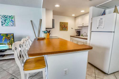 Il comprend une cuisine équipée d'un réfrigérateur blanc, d'une table et de chaises. dans l'établissement Sunset Chateau 207, à St. Pete Beach