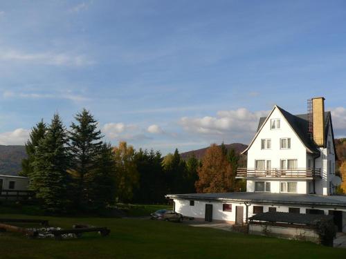 a white house sitting on top of a green field at Przystanek Smerek in Wetlina