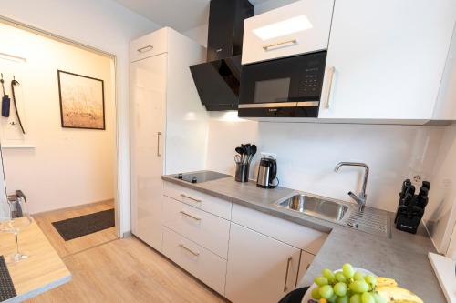 a kitchen with white cabinets and a sink at INhome Design Studio für 2 - Küche - Parkplatz - Netflix in Crailsheim