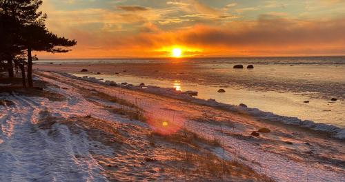 a sunset on the beach with snow on the ground at Dirhami Pool Villa in Dirhami