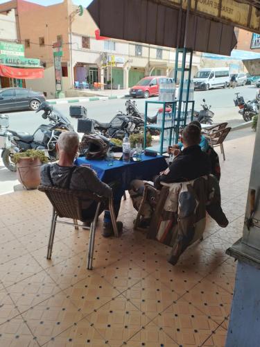 two men sitting at a table on a sidewalk at Auberge Restaurant Rooftop Tamazirt in Boumalne
