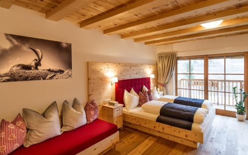 a bedroom with two beds and a red bench at Zum Alten Moar in Bressanone