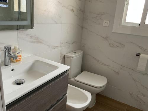 a white bathroom with a toilet and a sink at Casa con Gran Piscina particular cerca playa in Torredembarra