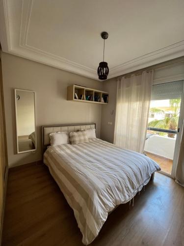 Appartement Casablanca Garden Beach في الدار البيضاء: غرفة نوم بسرير كبير ونافذة كبيرة