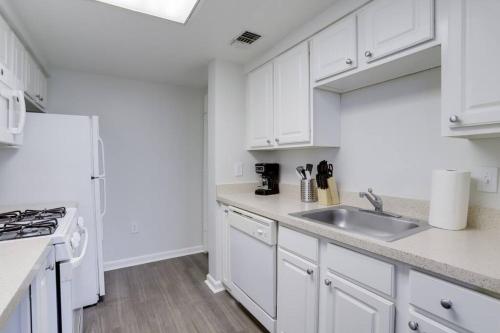 a kitchen with white cabinets and a sink at Stylish Condo Near Ballston Metro in Arlington