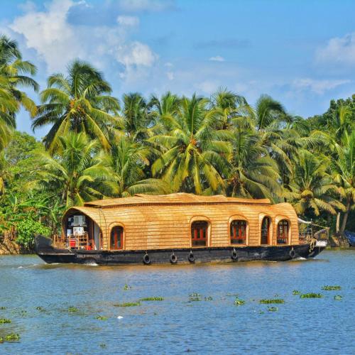 a house boat on the water with palm trees at Palmy Residency in Alleppey