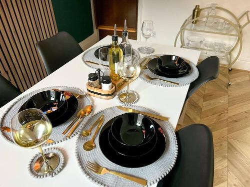 uma mesa branca com pratos pretos e copos de vinho em City centre terrace town house em Nottingham