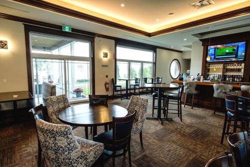 un restaurante con mesas y sillas y un bar en The Lakes at Ben Eoin Golf Club & Resort, en Sydney Forks