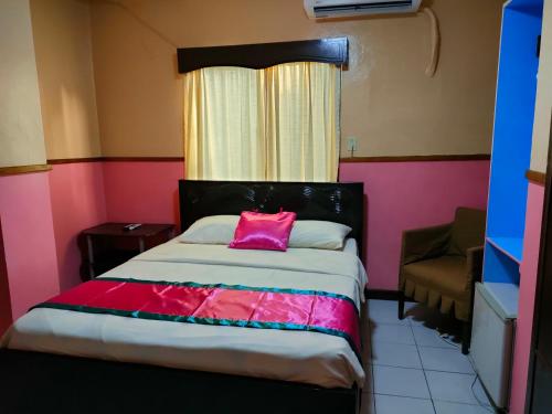 Dormitorio con cama con almohada rosa en LEHNS MOTEL, en Koror