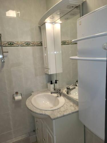 une salle de bain blanche avec un lavabo et un miroir dans l'établissement Appartement saisonnier, à Saint-Bonnet-en-Champsaur