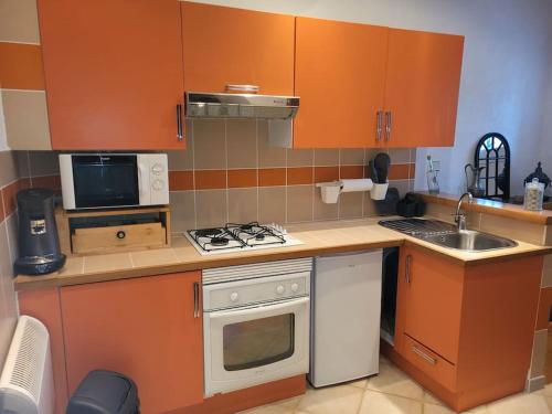 une petite cuisine avec des armoires orange et une cuisinière four supérieur dans l'établissement Appartement saisonnier, à Saint-Bonnet-en-Champsaur