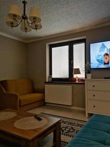 a living room with a couch and a tv at GOLD apartamenty & spa in Szczawnica