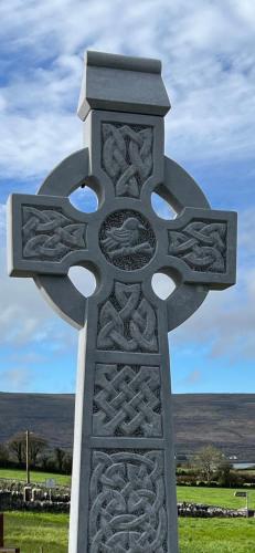 a monument with a cross on top of a field at Burren Court Lodge in Ballyvaughan