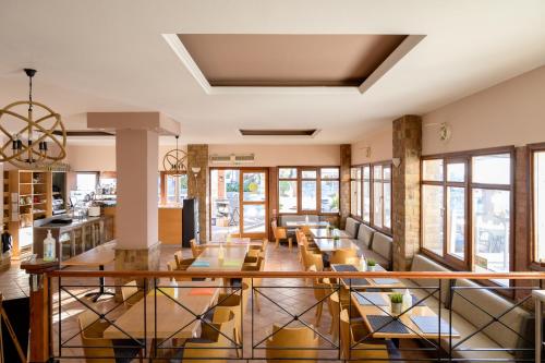 a dining room with tables and chairs and windows at Ilioxenia Chios Studios & Apartments in Paralia Agias Foteinis