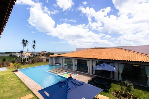 a house with a swimming pool and two umbrellas at Casa Sirenia in Cajueiro