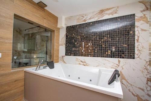 La salle de bains est pourvue d'une baignoire blanche et d'un mur en carrelage noir. dans l'établissement Hotel Grand, à Banja Luka
