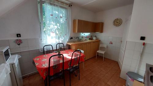 eine Küche mit einem roten Tisch und Stühlen sowie einem Fenster in der Unterkunft Malomtavi Vendégház in Tapolca
