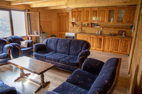 a living room with a blue couch and chairs at Mariash Woodhouse - Beleg Mountains in Deçan